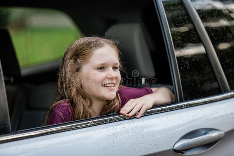 Little caucasian girl with freckles and a purple shirt looking out of a car window and looking away. Little caucasian girl with freckles and a purple shirt looking out of a car window and looking away.