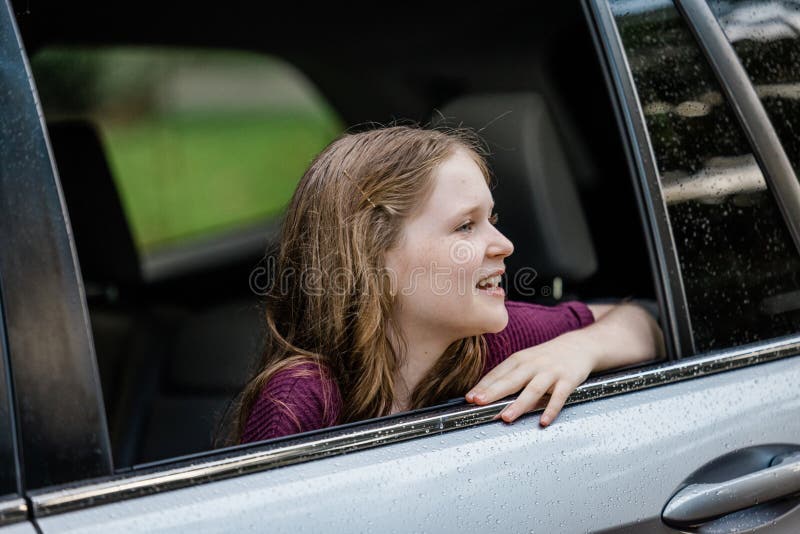 Little caucasian girl with freckles and a purple shirt looking out of a car window and looking away. Little caucasian girl with freckles and a purple shirt looking out of a car window and looking away.