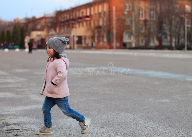 pequeña muchacha blanca que camina abajo de la calle por la tarde Retrato en el fondo del paisaje urbano de la puesta del sol fotografía de archivo libre de regalías pequeña muchacha blanca que camina abajo de la calle por la tarde Retrato en el fondo del paisaje urbano de la puesta del sol fotografía de archivo libre de regalías