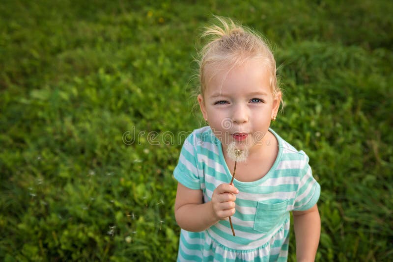 Pequeña muchacha rubia adorable con la flor del diente de león imagen de archivo Pequeña muchacha rubia adorable con la flor del diente de león imagen de archivo