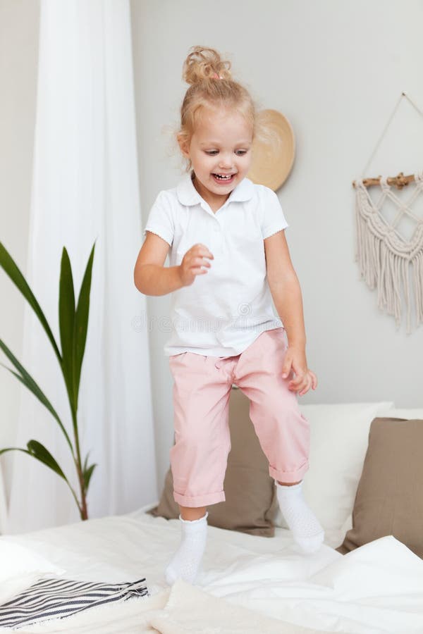 Pequeña muchacha sonriente bonita del retrato que juega y que salta en dormitorio fotografía de archivo libre de regalías Pequeña muchacha sonriente bonita del retrato que juega y que salta en dormitorio fotografía de archivo libre de regalías