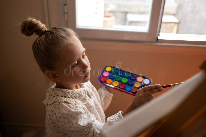Pequeña niña linda dibuja con pinturas sobre lienzo en la comadreja imágenes de archivo libres de regalías
