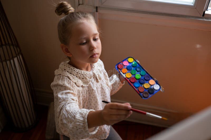 Pequeña niña linda dibuja con pinturas sobre lienzo en la comadreja foto de archivo libre de regalías