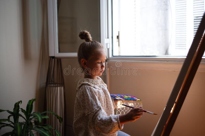 Pequeña niña linda dibuja con pinturas sobre lienzo en la comadreja. el concepto de desarrollo temprano de talentos infantiles. fotografía de archivo libre de regalías