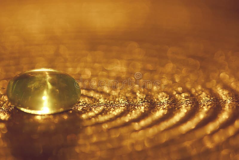 Pequeña piedra de cristal en una placa con las chispas y el bokeh de oro imágenes de archivo libres de regalías Pequeña piedra de cristal en una placa con las chispas y el bokeh de oro imágenes de archivo libres de regalías