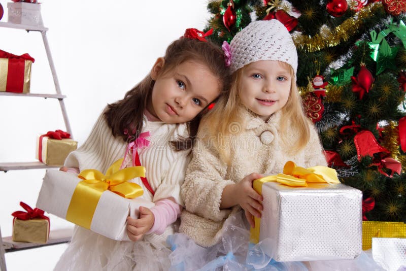 Pequeñas hermanas con los presentes debajo del árbol de navidad foto de archivo Pequeñas hermanas con los presentes debajo del árbol de navidad foto de archivo