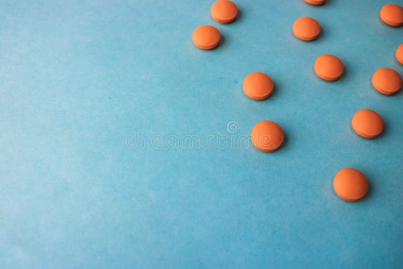 Pequeñas píldoras redondas pharmaceptic médicas hermosas amarillo-naranja, vitaminas, drogas, antibióticos en un fondo azul, text imagen de archivo Pequeñas píldoras redondas pharmaceptic médicas hermosas amarillo-naranja, vitaminas, drogas, antibióticos en un fondo azul, text imagen de archivo