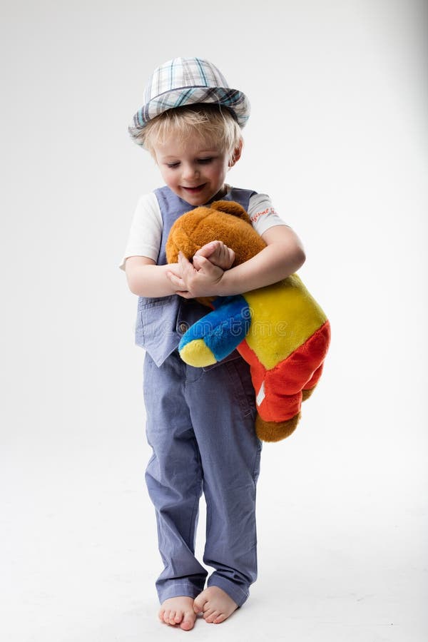 Pequeño bebé con el sombrero que abraza su oso de peluche imagen de archivo Pequeño bebé con el sombrero que abraza su oso de peluche imagen de archivo