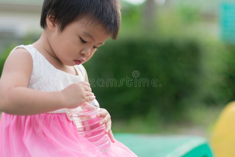 Pequeño intento lindo asiático de la muchacha para cerrar la botella plástica de limpio fotografía de archivo libre de regalías Pequeño intento lindo asiático de la muchacha para cerrar la botella plástica de limpio fotografía de archivo libre de regalías