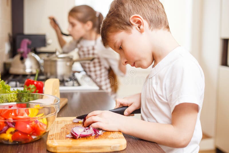 Pequeño muchacho que cocina así como su hermana fotografía de archivo libre de regalías Pequeño muchacho que cocina así como su hermana fotografía de archivo libre de regalías