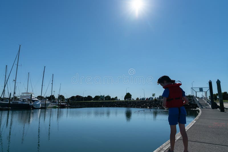 Pequeño muchacho silueteado contra la pesca del sol de la mañana fotografía de archivo