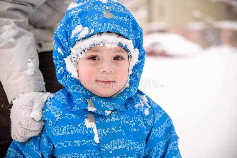 Pequeño muchacho sonriente feliz al aire libre en la nieve en ropa del invierno El niño tiene una helada en su cara fotos de archivo libres de regalías Pequeño muchacho sonriente feliz al aire libre en la nieve en ropa del invierno El niño tiene una helada en su cara fotos de archivo libres de regalías