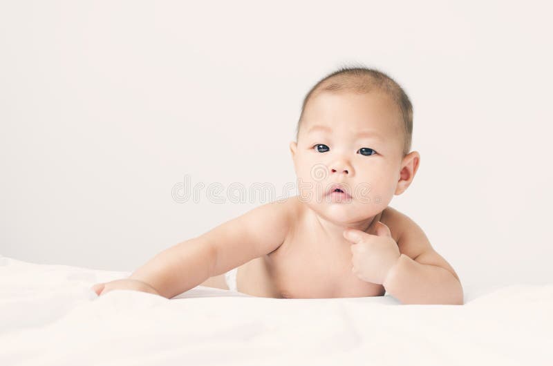 Pequeño pequeño niño asiático del bebé que pone en cama después de baño fotos de archivo Pequeño pequeño niño asiático del bebé que pone en cama después de baño fotos de archivo