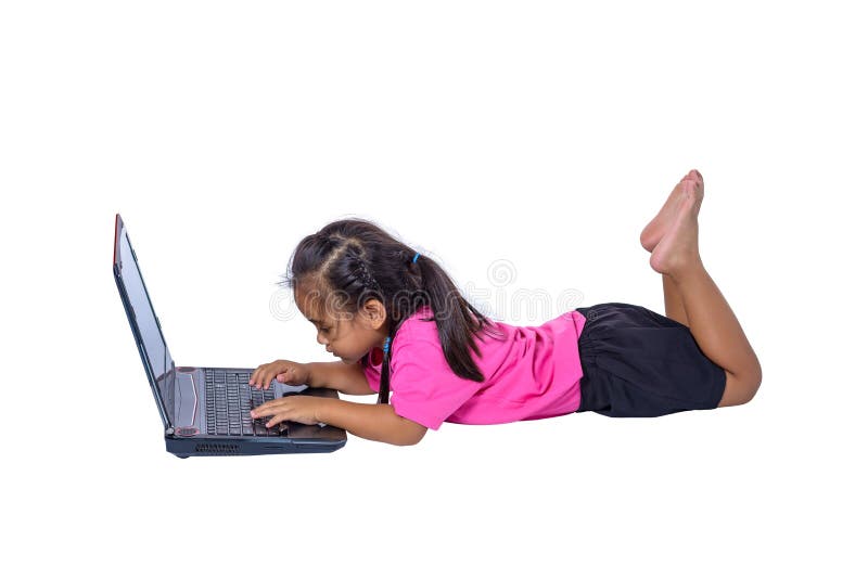 Pequeño niño asiático lindo de la muchacha que miente en el piso que estudia o que usa el ordenador portátil aislado en el fondo foto de archivo libre de regalías Pequeño niño asiático lindo de la muchacha que miente en el piso que estudia o que usa el ordenador portátil aislado en el fondo foto de archivo libre de regalías
