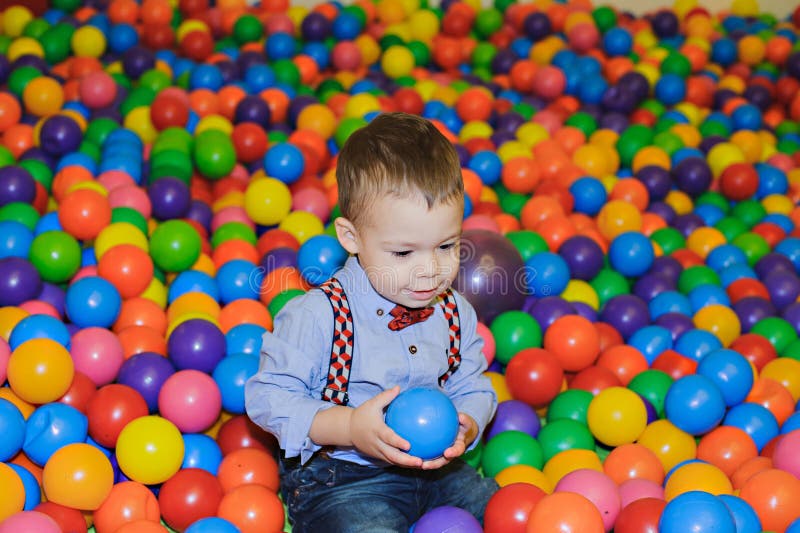 Pequeño niño feliz que juega en el patio plástico colorido de las bolas fotos de archivo libres de regalías Pequeño niño feliz que juega en el patio plástico colorido de las bolas fotos de archivo libres de regalías