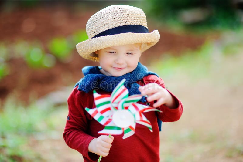 Pequeño niño lindo que sostiene el molino de viento del juguete fotos de archivo libres de regalías Pequeño niño lindo que sostiene el molino de viento del juguete fotos de archivo libres de regalías
