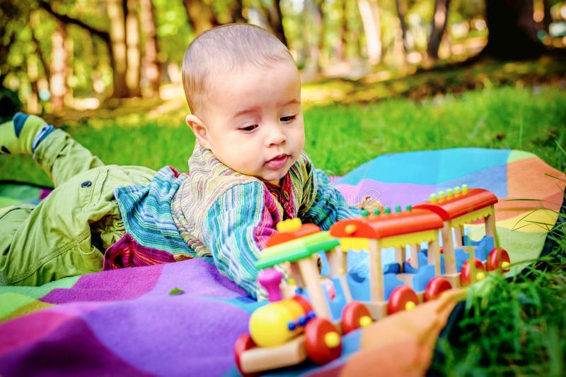 Pequeño niño pequeño adorable que pone en la tierra en el parque y PAL imagen de archivo libre de regalías Pequeño niño pequeño adorable que pone en la tierra en el parque y PAL imagen de archivo libre de regalías
