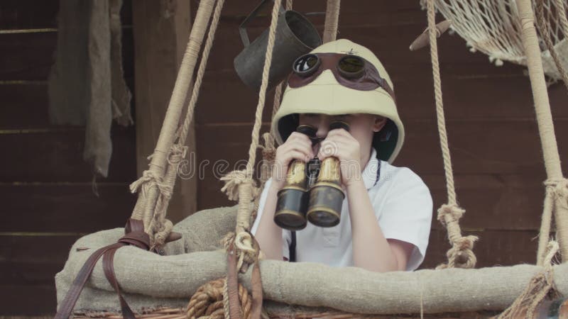 Pequeño niño que juega al explorador, mirando con la situación binocular en balón de aire