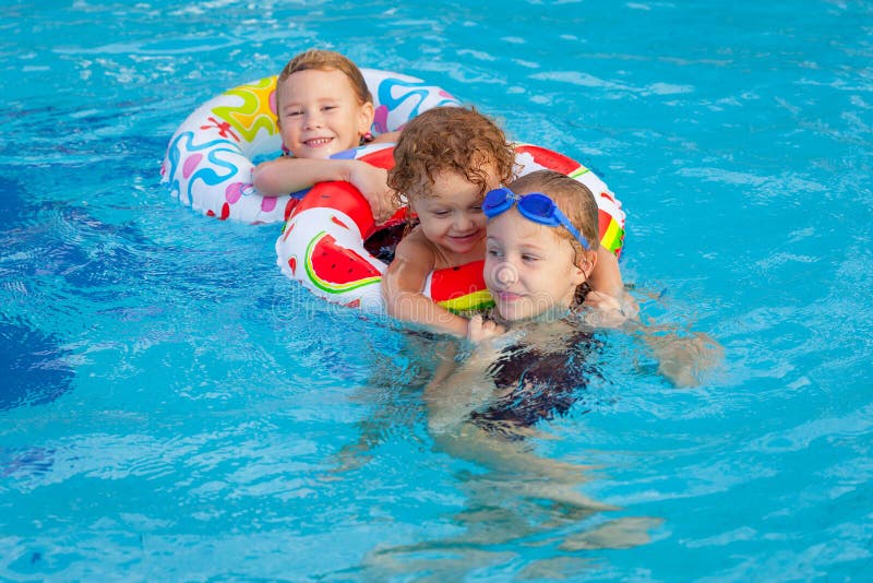 Pequeños niños felices que juegan en la piscina imagen de archivo Pequeños niños felices que juegan en la piscina imagen de archivo