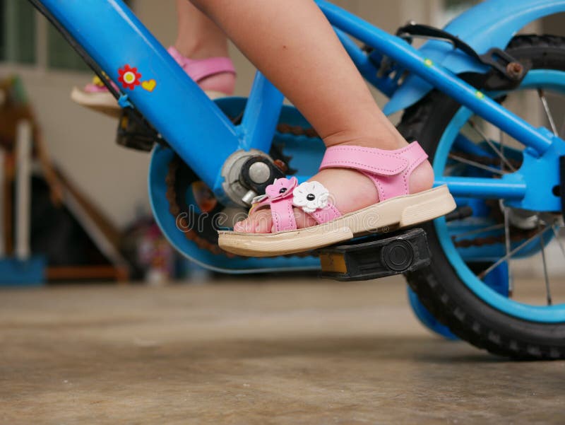 Pequeños pies del ` s del bebé en los pedales que aprenden montar una bicicleta con las ruedas de entrenamiento fotos de archivo Pequeños pies del ` s del bebé en los pedales que aprenden montar una bicicleta con las ruedas de entrenamiento fotos de archivo