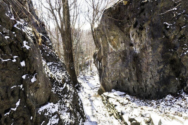 Percorso innevato stretto attraverso i massi e le rocce, alberi alti, fotografia stock libera da diritti Percorso innevato stretto attraverso i massi e le rocce, alberi alti, fotografia stock libera da diritti
