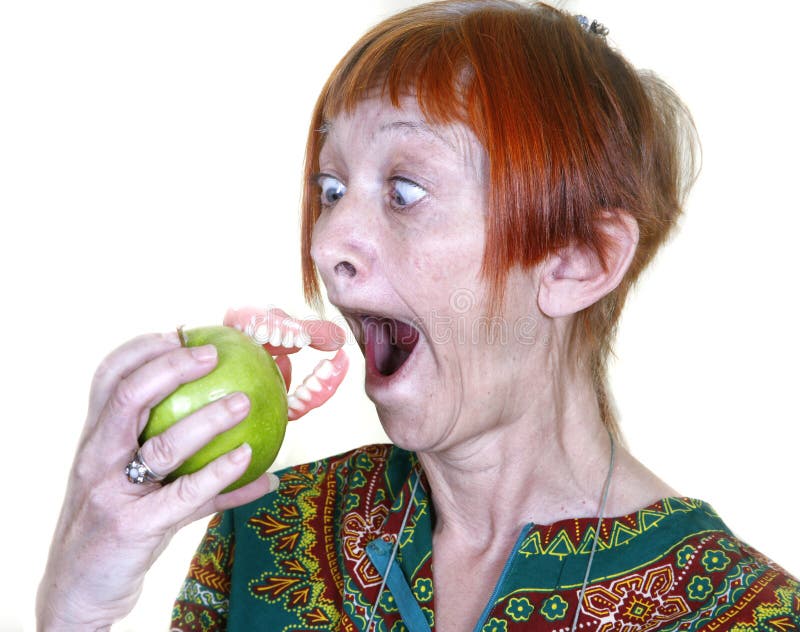 Woman losing her false teeth by biting into an apple. Woman losing her false teeth by biting into an apple