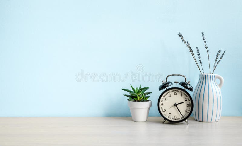 Perete albastru gol și birou cu ceas deșteptător pentru casă și vază ceramică. copiere spațiu royalty free stock image