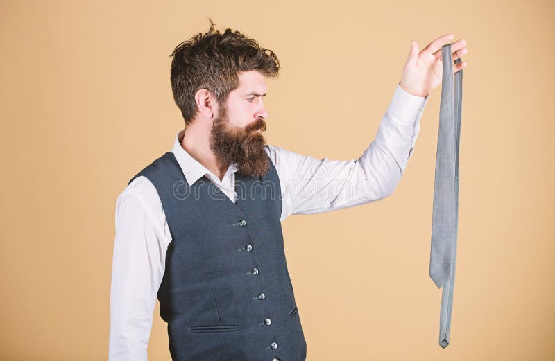 The perfect accessory for any man. Businessman looking at formal necktie accessory. Brutal caucasian man holding fashion accessory. Bearded man choosing status accessory.