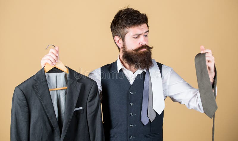 A perfect choice. Businessman choosing necktie, choice concept. Bearded man matching tie color to suit jacket in store. Hipster making shopping choice in shop. Choice of clothes and accessories.
