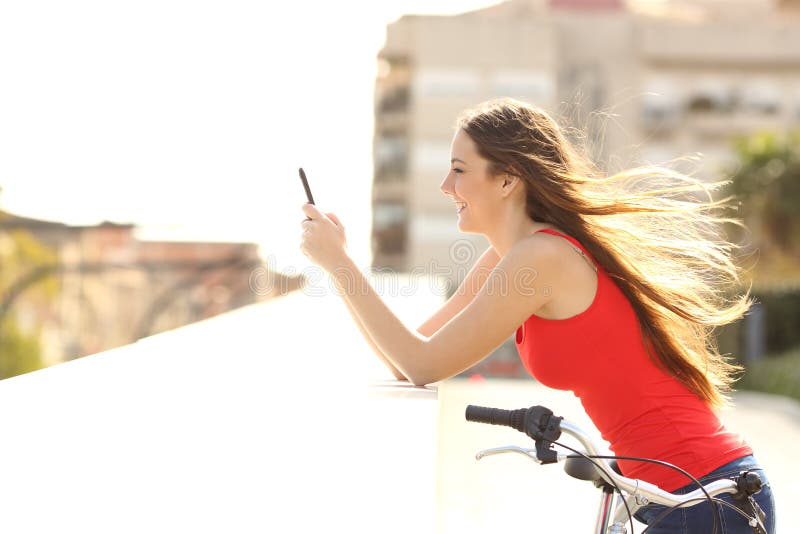 Perfil de uma menina adolescente que usa um telefone celular em um parque fotografia de stock royalty free Perfil de uma menina adolescente que usa um telefone celular em um parque fotografia de stock royalty free