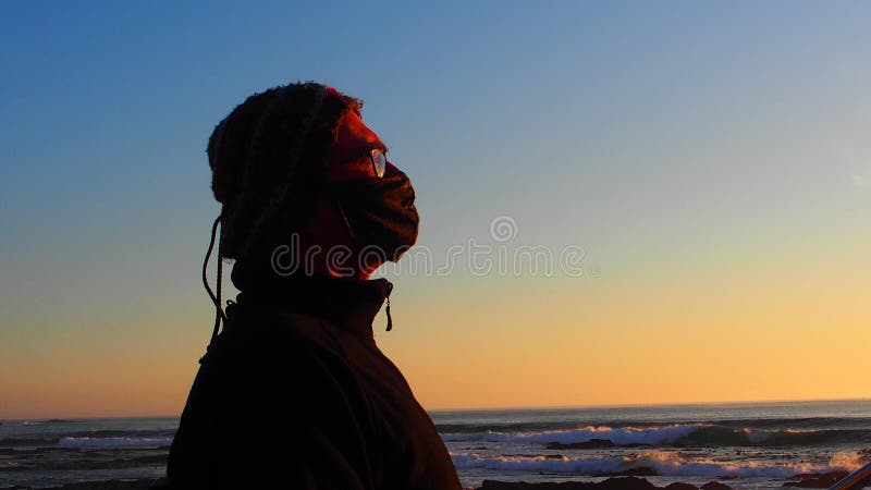 Side profile of man wearing a mask looking at the ocean and sunset in Cape Town, Sea Point. Side profile of man wearing a mask looking at the ocean and sunset in Cape Town, Sea Point