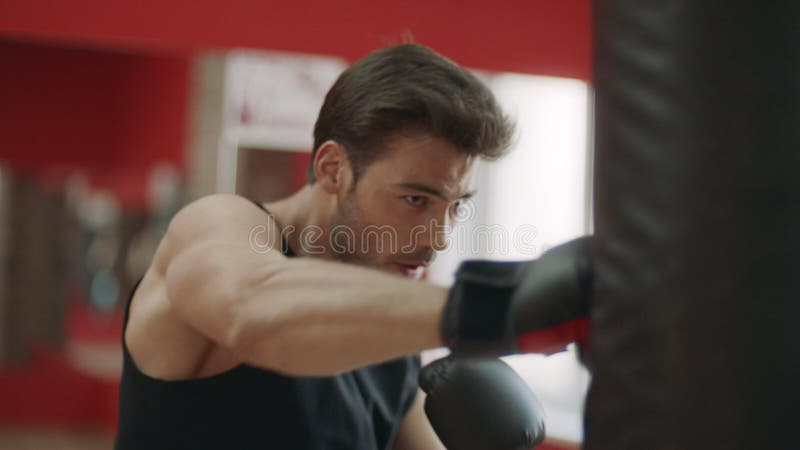 Perforazioni di addestramento dell'uomo di Kickboxer sulla borsa di combattimento nel club di lotta