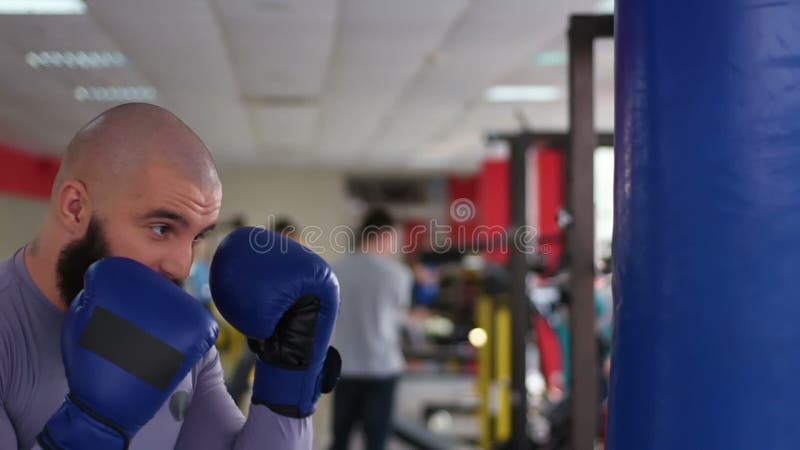 Perforazioni di pratica del pugile maschio professionista sulla borsa di pugilato, funzionamento duro in palestra