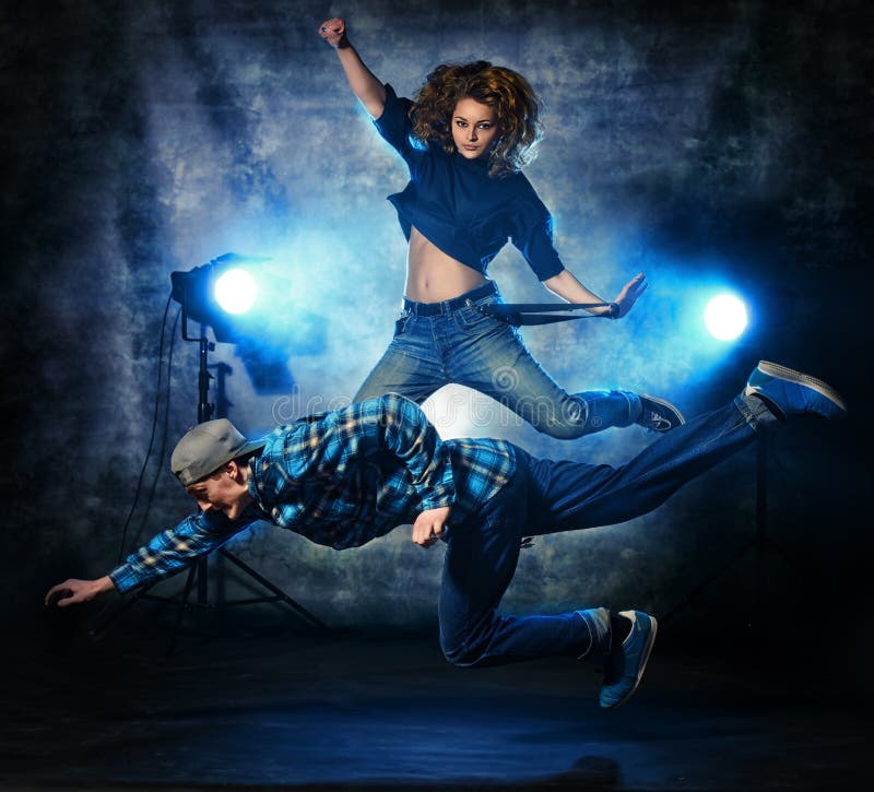 Two modern dancers jumping over grunge background. Hip-hop. Urban, disco style. Two modern dancers jumping over grunge background. Hip-hop. Urban, disco style.