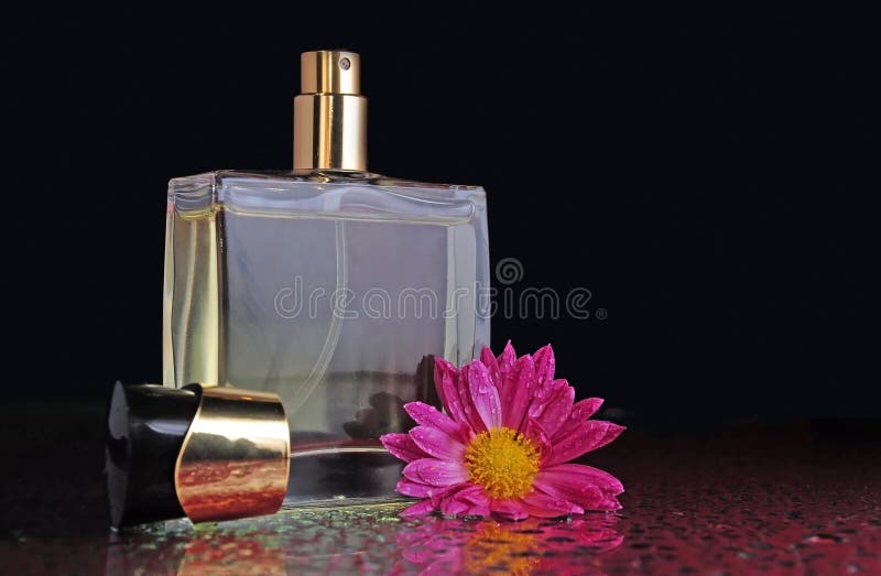 A bottle of perfume with a flower on a table with splashes. A bottle of perfume with a flower on a table with splashes.