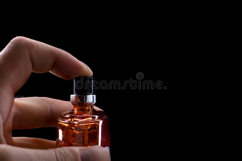 Perfume bottle in hand isolated on black