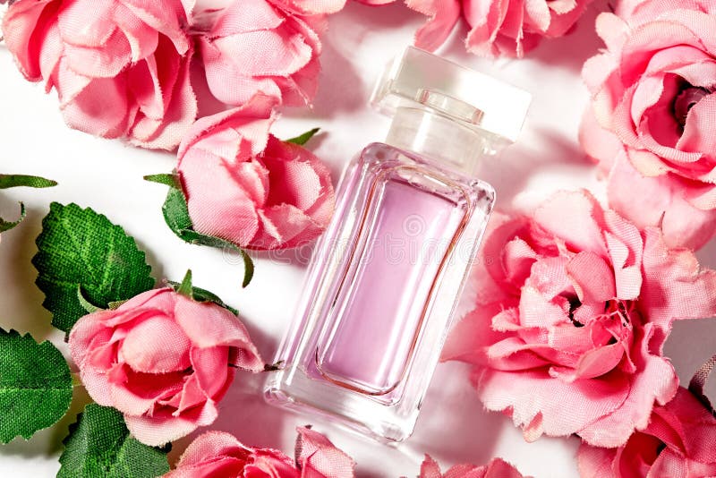 Perfume bottle in pink flower roses. Spring background with luxury aroma parfume. Beauty cosmetic shot