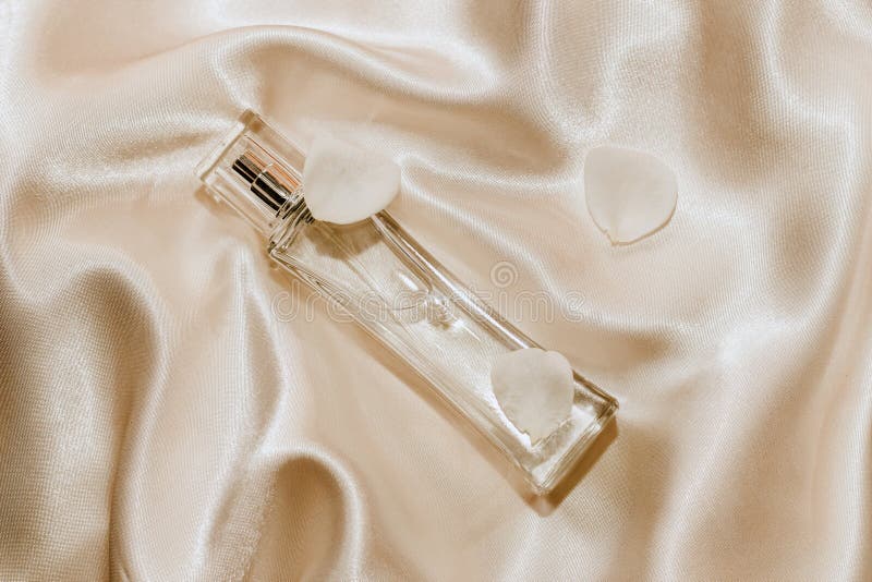 Perfume Bottle and White Flower Petals on a Silk Beige Background ...