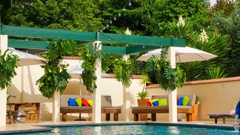 A luxury home with pool, outdoor furniture and lush tropical trees. Colourful cushions. A luxury home with pool, outdoor furniture and lush tropical trees. Colourful cushions.