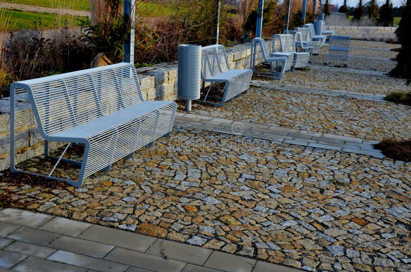 arched pergolas made of gray metal frames for climbing plants. benches and chairs of transparent wire furniture. dry garden walls and tall ornamental grasses sandy paths, sunlight, sunset, perennial. arched pergolas made of gray metal frames for climbing plants. benches and chairs of transparent wire furniture. dry garden walls and tall ornamental grasses sandy paths, sunlight, sunset, perennial