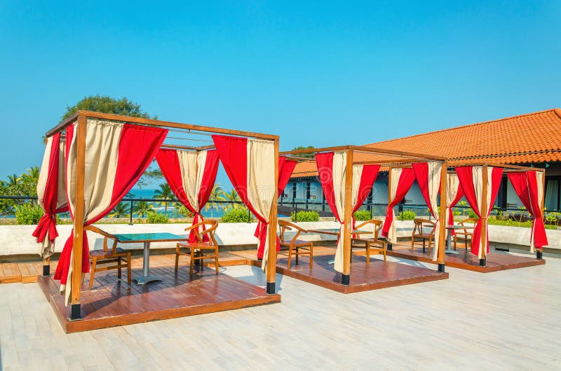 Pergolas with tables and chairs, red curtains on restaurant of luxury hotel on a sunny day. Pergolas with tables and chairs, red curtains on restaurant of luxury hotel on a sunny day