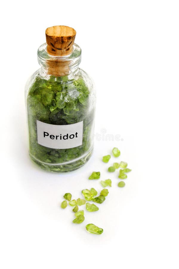 An image showing a geological sample of raw peridot rocks in olive green color, kept in an antique clear glass bottle with cork. Hobby image for rock collecting. Some peridot stones scattered on white table in front of bottle. Vertical color image with sparse composition and clean white background, copy space. Peridot is the august birthstone. An image showing a geological sample of raw peridot rocks in olive green color, kept in an antique clear glass bottle with cork. Hobby image for rock collecting. Some peridot stones scattered on white table in front of bottle. Vertical color image with sparse composition and clean white background, copy space. Peridot is the august birthstone.