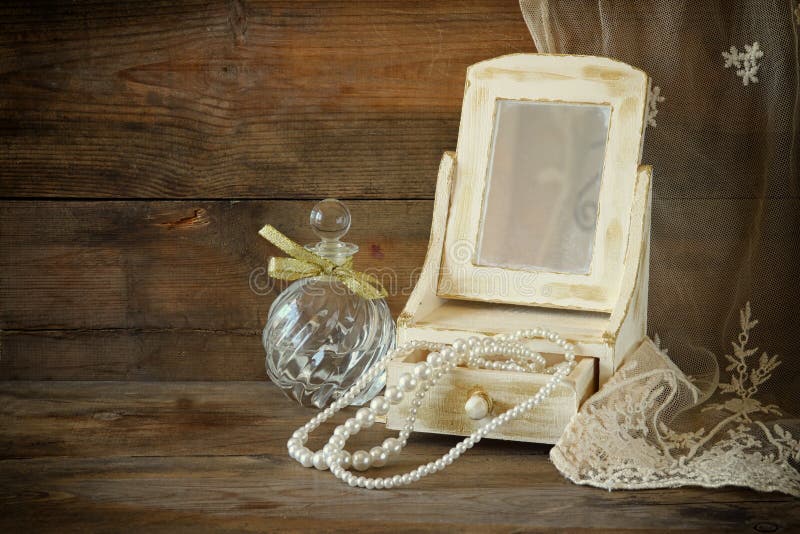 Vintage pearls , antique wooden jewelry box with mirror and perfume bottle on wooden table. filtered image. Vintage pearls , antique wooden jewelry box with mirror and perfume bottle on wooden table. filtered image.