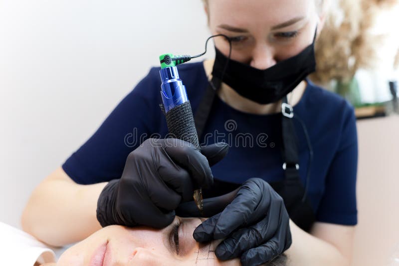 Permanent Makeup Artist Leans Over the Client and Performs an Eyebrow Tattoo Stock Image - Image of machine, permanent: 221658051 Permanent Makeup Artist Leans Over the Client and Performs an Eyebrow Tattoo Stock Image - Image of machine, permanent: 221658051