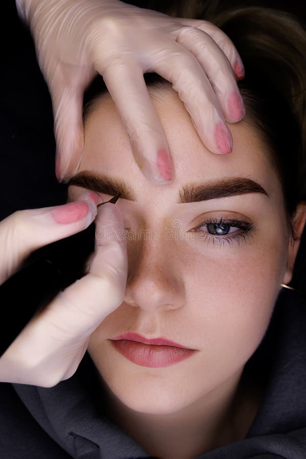 Permanent Makeup of the Eyebrows, the Master Holds the Eyebrow of the