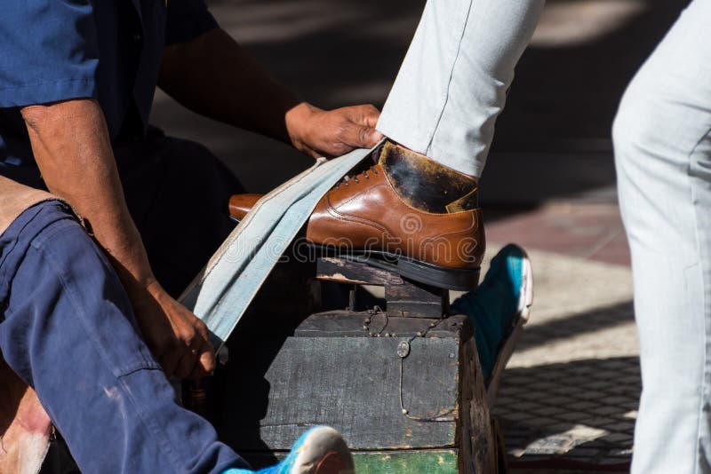 person brushing a customer& x27;s leather shoes on the sidewalk of the city
