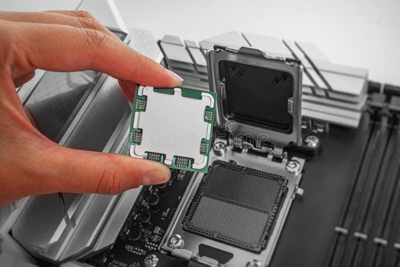 A person is carefully holding a computer processor above a motherboard socket stock photo