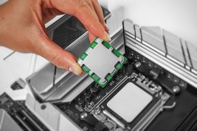 A person is carefully holding a computer processor above a motherboard socket stock image