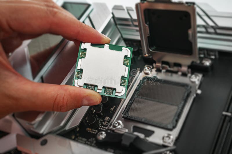 A person is carefully holding a computer processor above a motherboard socket royalty free stock photos
