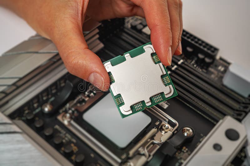 A person is carefully holding a computer processor above a motherboard socket stock photo